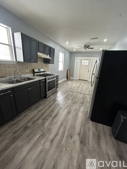 A kitchen with black cabinets and a wooden floor.