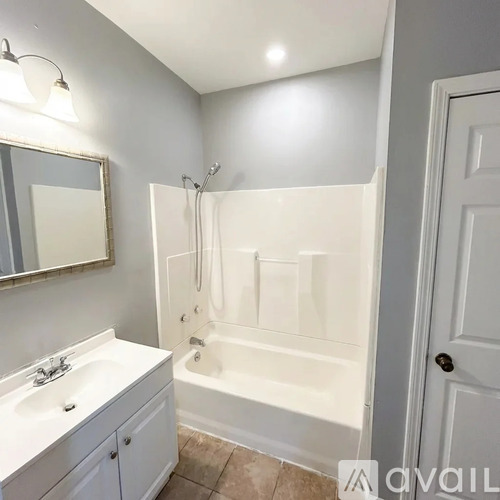 A white bathroom with a tub, sink, and mirror.