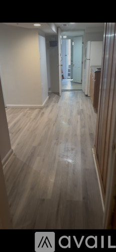 A hallway with wooden floors and white walls.
