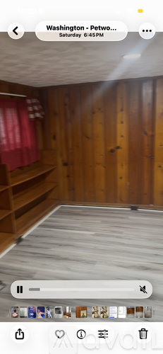 A room with wooden walls and a bed in the foreground.