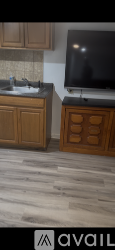 A kitchen with wooden cabinets and a black television.