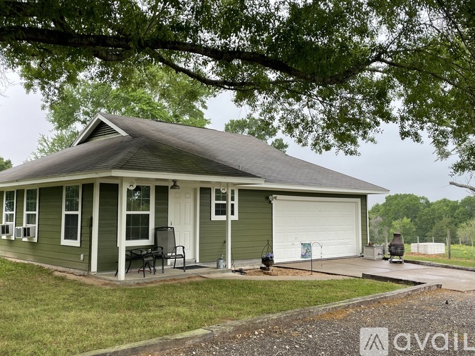 A green house with a white garage door and a patio with a table and chairs.