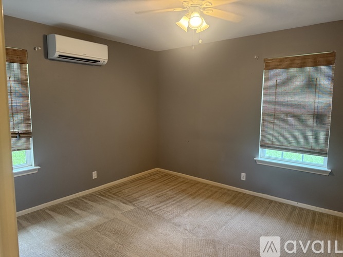 A room with a ceiling fan and two windows.