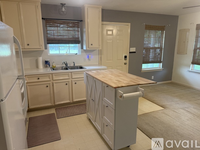 A kitchen with a refrigerator, sink, and cabinets.