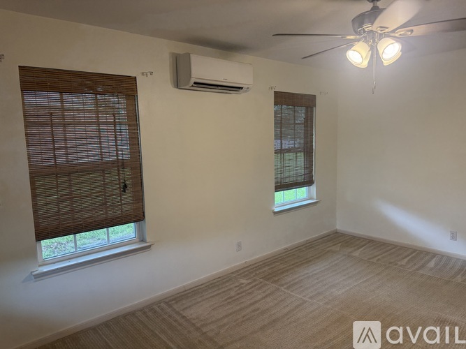 A room with a ceiling fan and two windows with blinds.