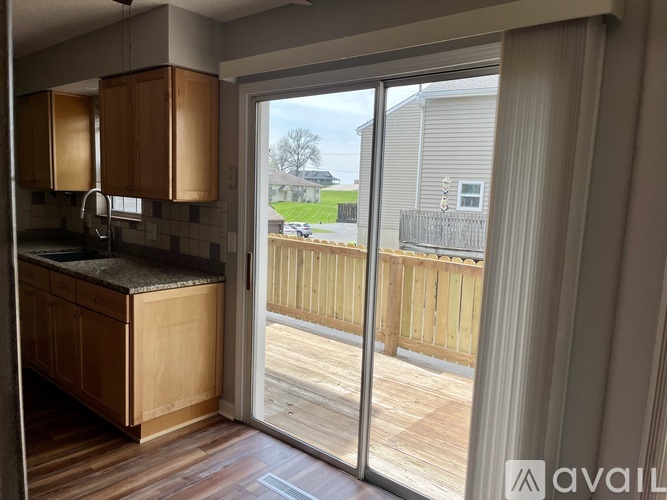 A kitchen with wooden cabinets and a sliding glass door leading to a wooden deck.