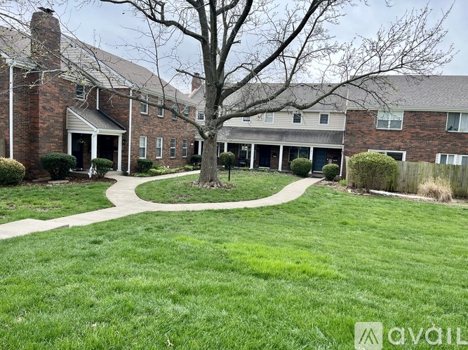 A grassy area in front of a brick building with a tree in the middle.