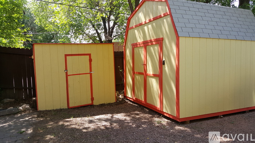 Two yellow sheds with red trim and doors.
