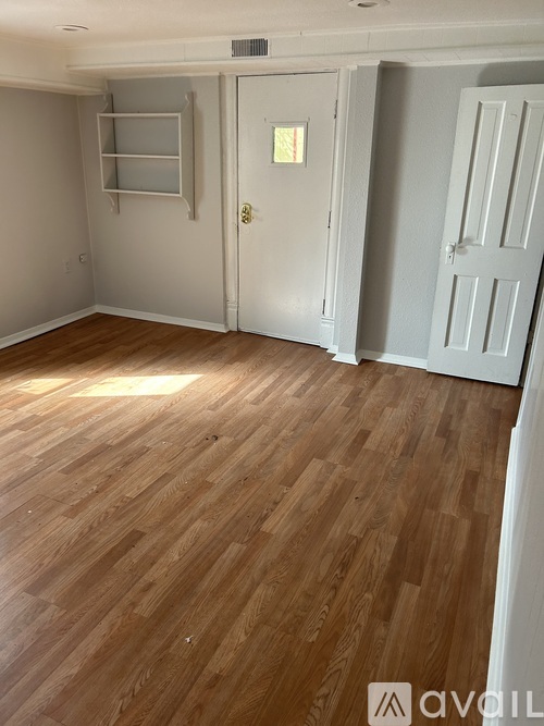 A room with wooden flooring and white walls.