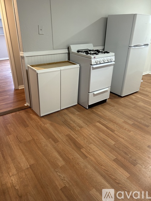 A kitchen with a white stove and refrigerator, and a white cabinet.