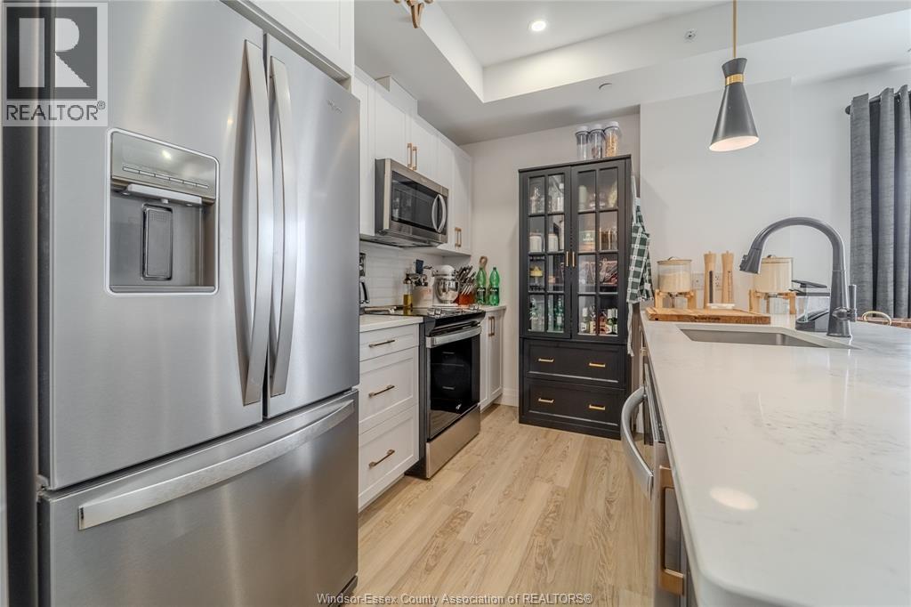 A modern kitchen with a stainless steel refrigerator and wooden flooring.