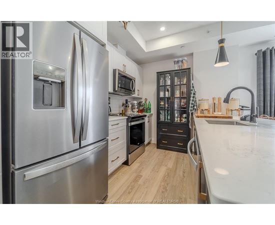 A modern kitchen with a stainless steel refrigerator and wooden flooring.