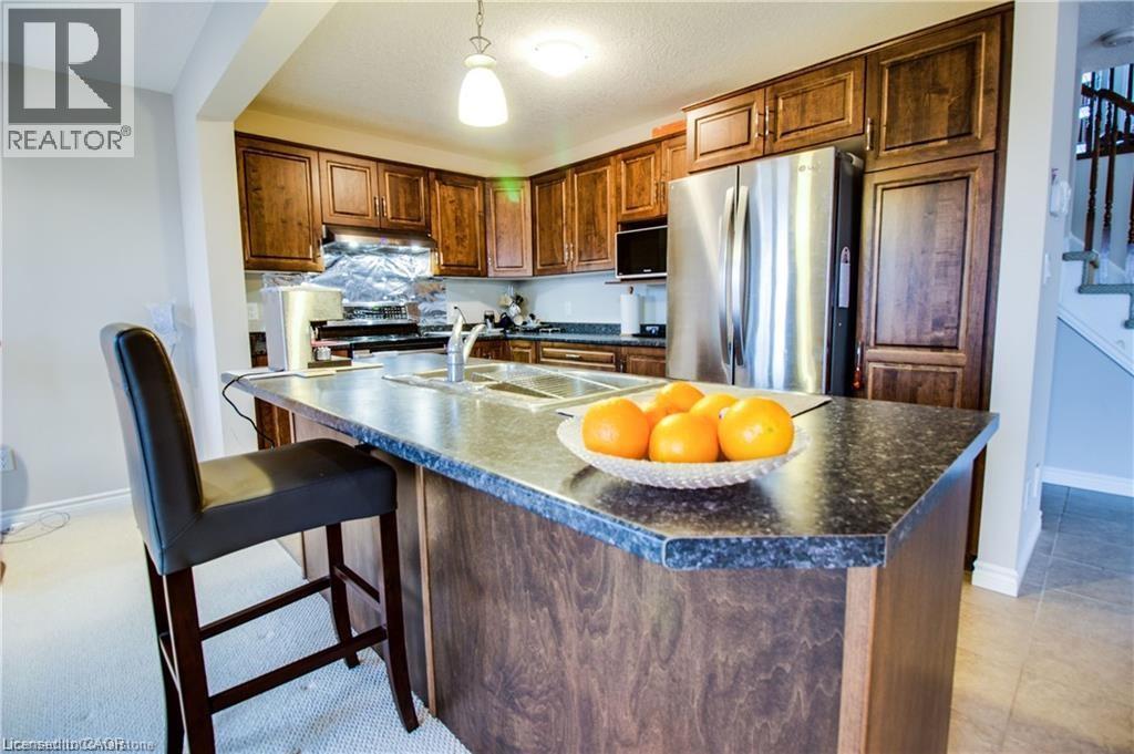 A kitchen with a black chair and a bowl of oranges on the island.