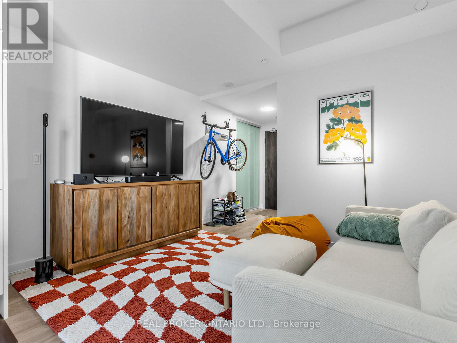A living room with a white couch and a red and white checkered rug.
