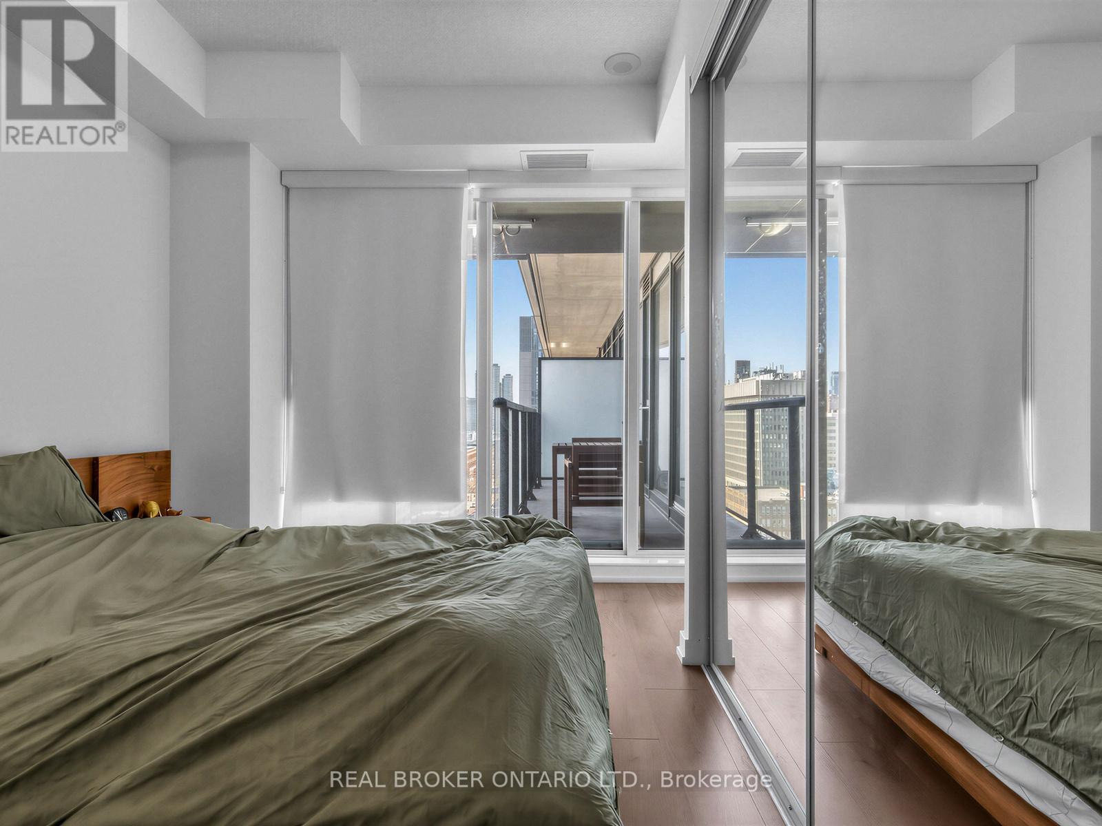 A bedroom with a large bed and a view of the city through the window.