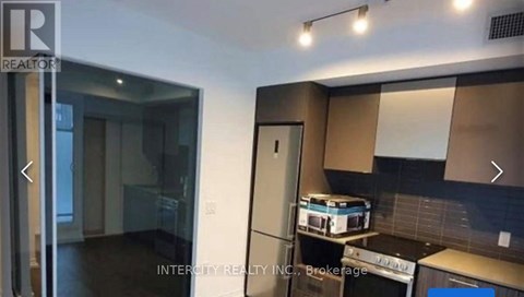 A kitchen with a refrigerator, microwave, and oven.