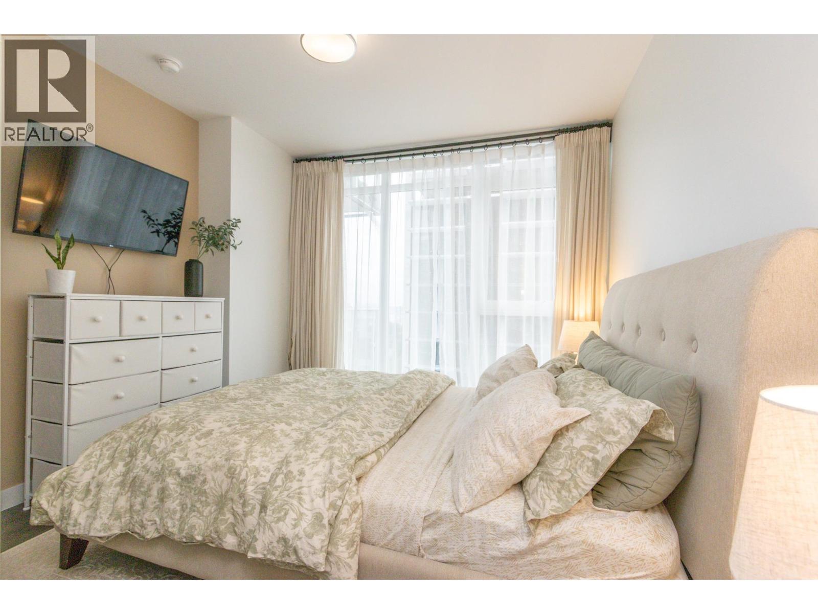 A bedroom with a bed, dresser, and window.