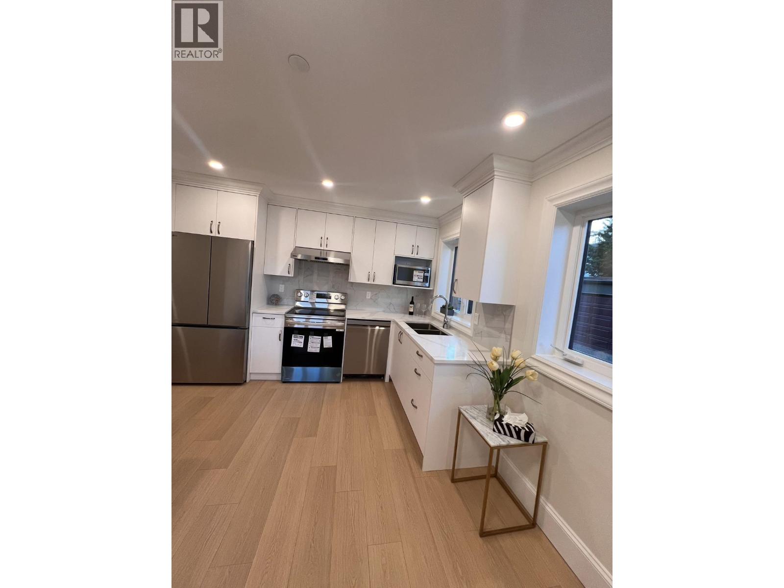 A modern kitchen with wooden floors and white walls.