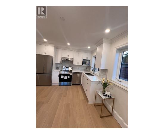 A modern kitchen with wooden floors and white walls.