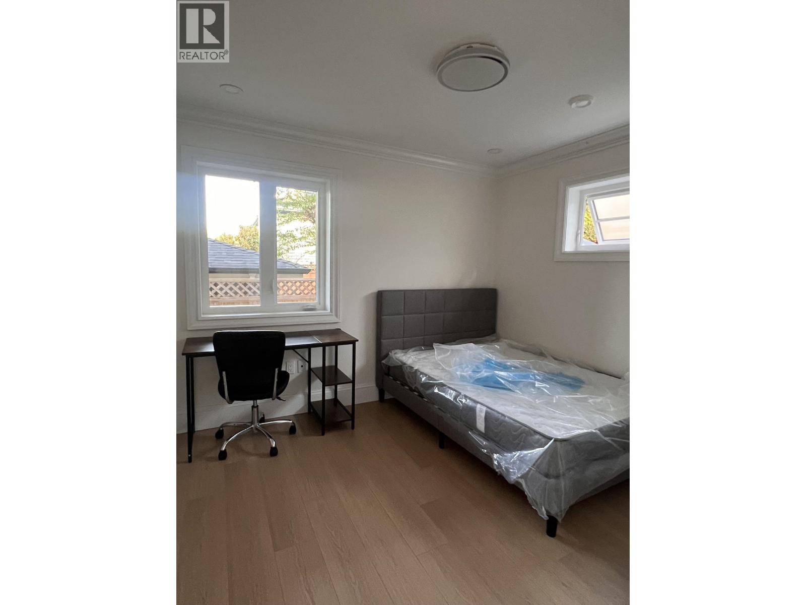 A bedroom with a bed, desk, and chair.