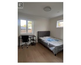 A bedroom with a bed, desk, and chair.