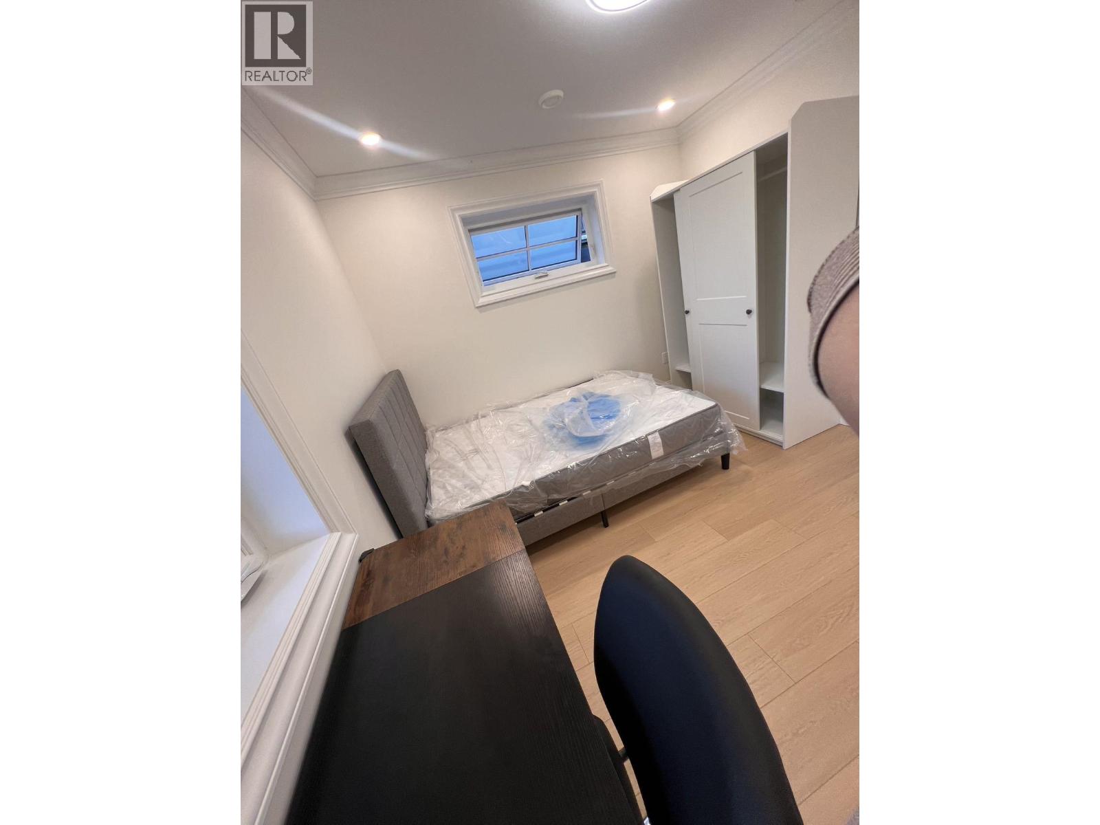 A bedroom with a bed, chair, and window.