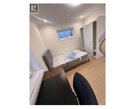 A bedroom with a bed, chair, and window.