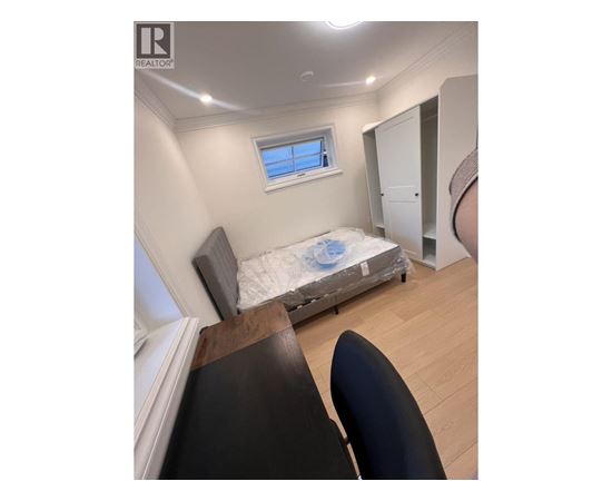 A bedroom with a bed, chair, and window.