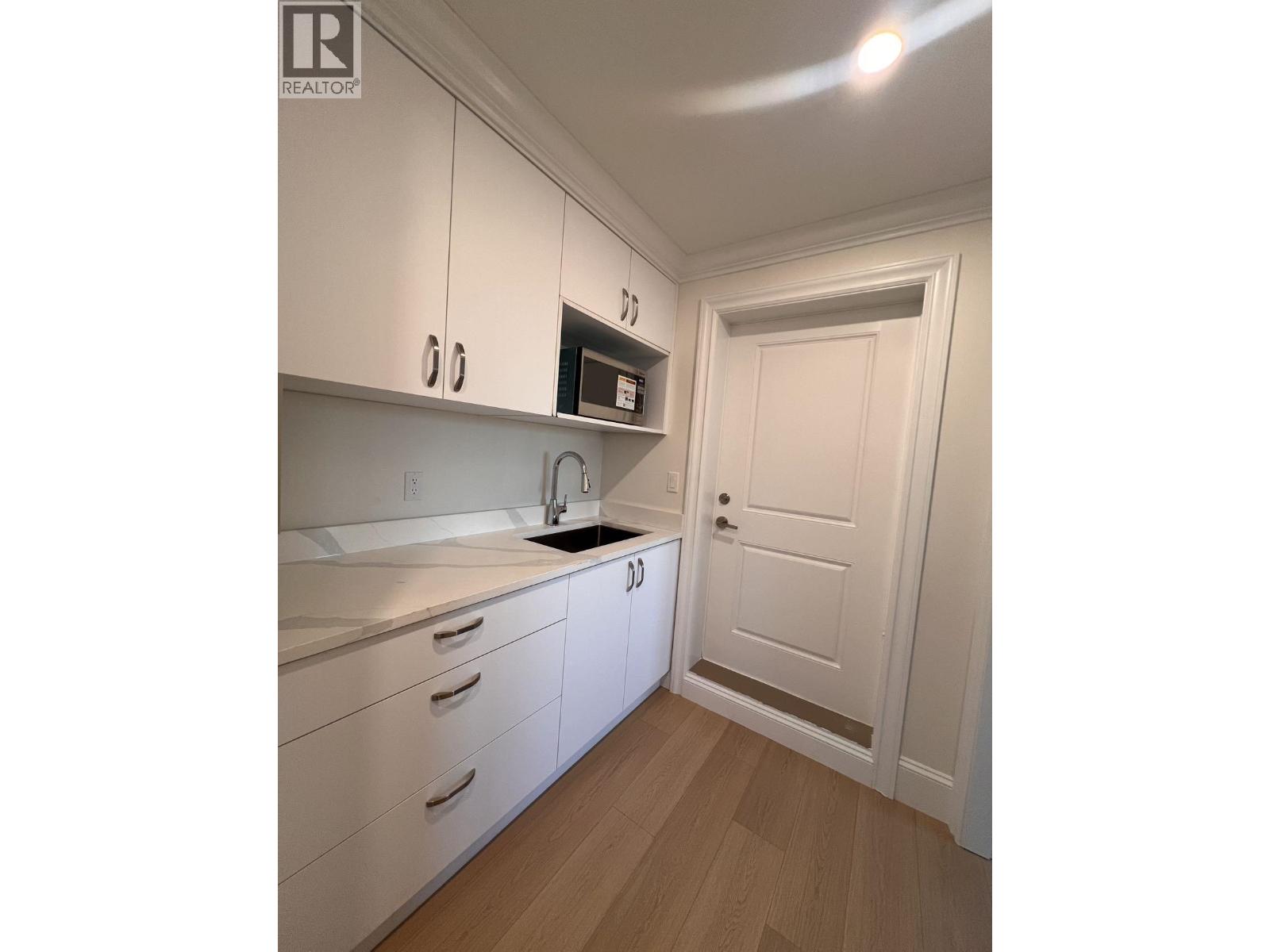 A kitchen with white cabinets and a wooden floor.