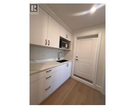 A kitchen with white cabinets and a wooden floor.