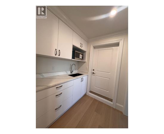 A kitchen with white cabinets and a wooden floor.
