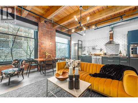 A living room with a yellow couch and a wooden table.
