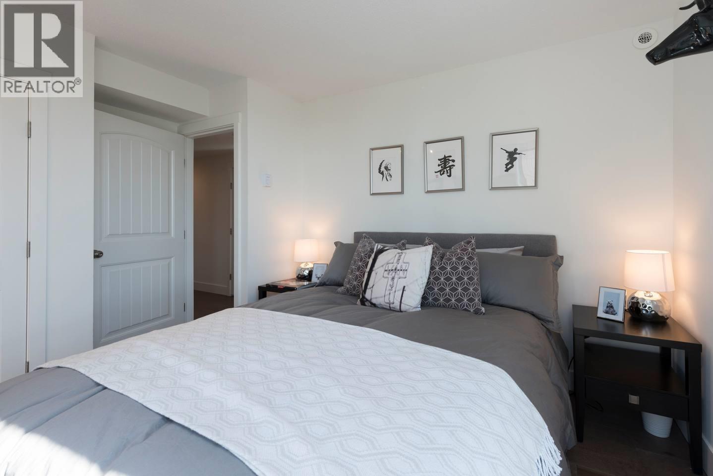 A bedroom with a large bed and a nightstand with a lamp.