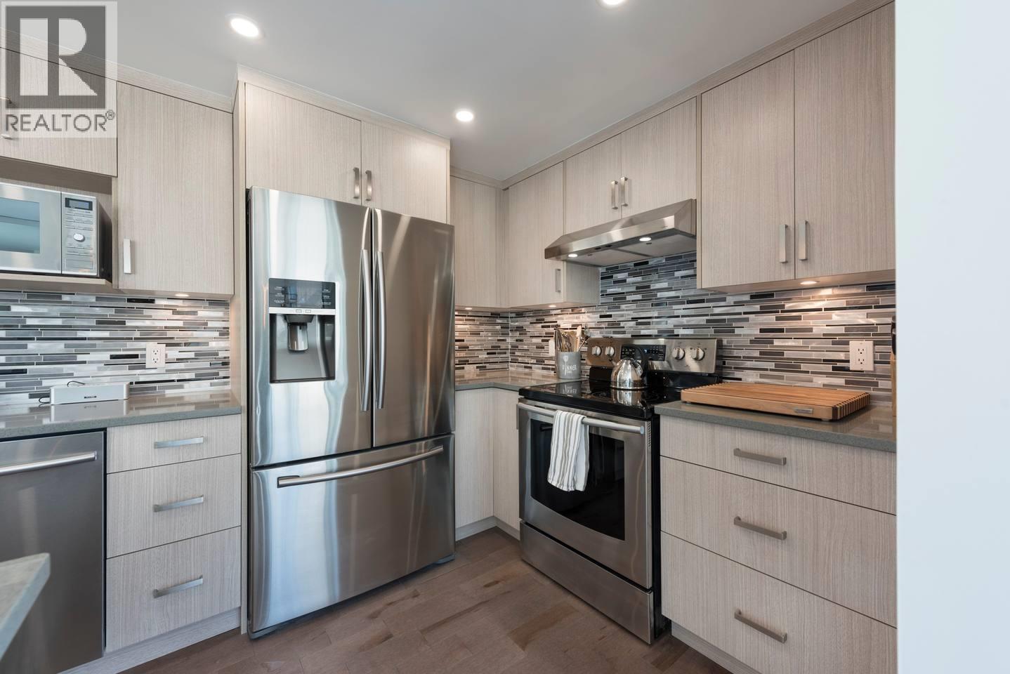 A modern kitchen with a stainless steel refrigerator and oven.