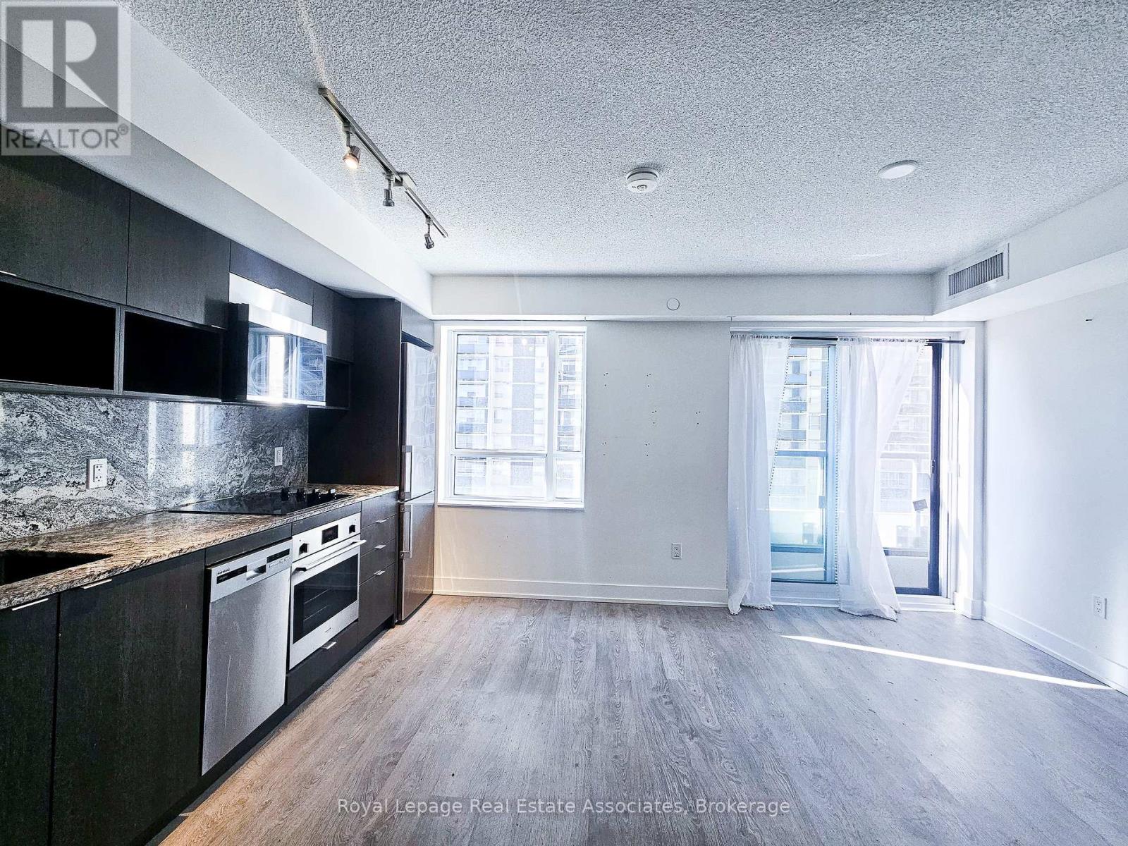 A spacious kitchen with dark cabinets and stainless steel appliances.