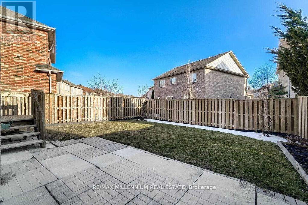 A backyard with a wooden fence and a brick building in the background.