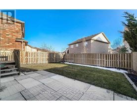 A backyard with a wooden fence and a brick building in the background.