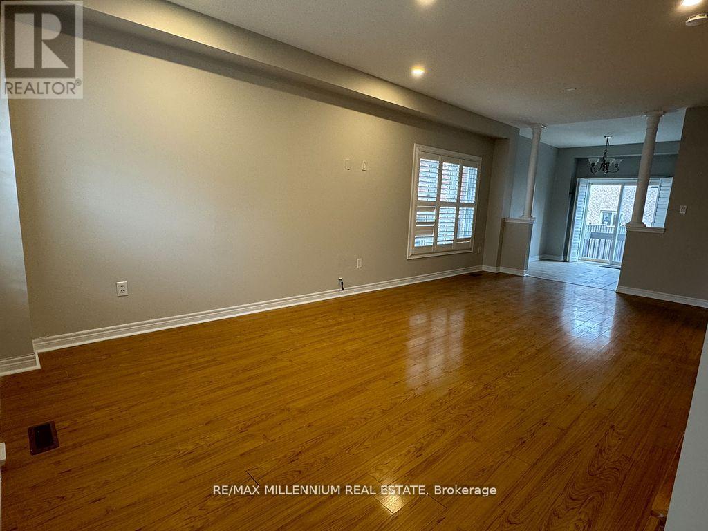 A spacious room with wooden flooring and a window.