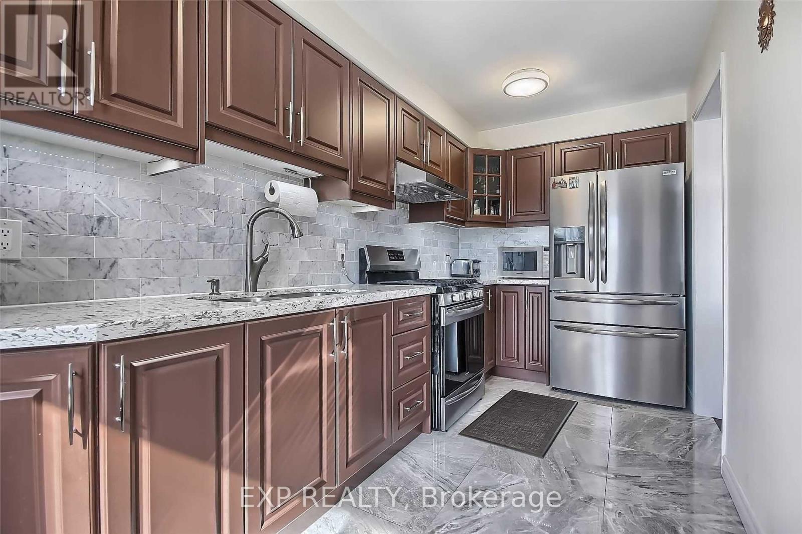 A kitchen with brown cabinets and a marble countertop.
