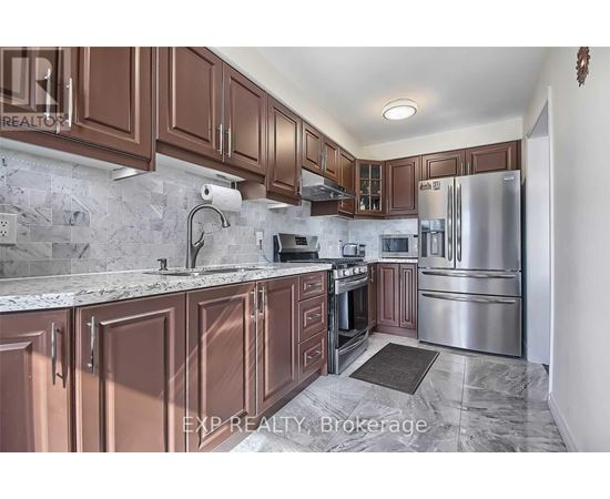 A kitchen with brown cabinets and a marble countertop.