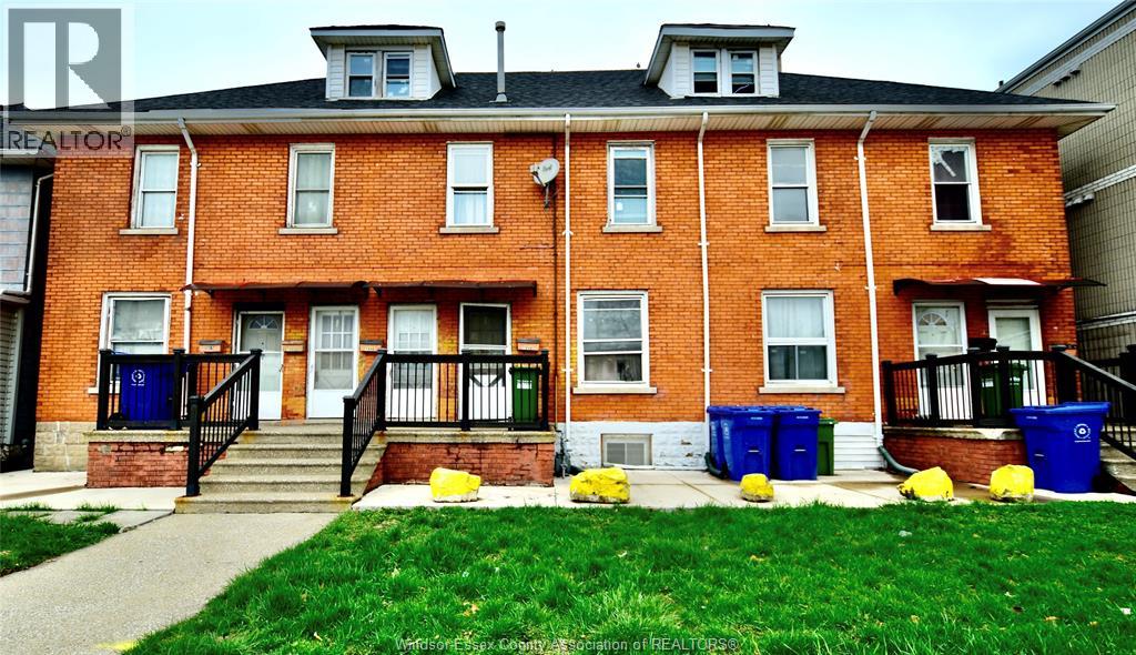 A red brick building with a balcony and a small porch.