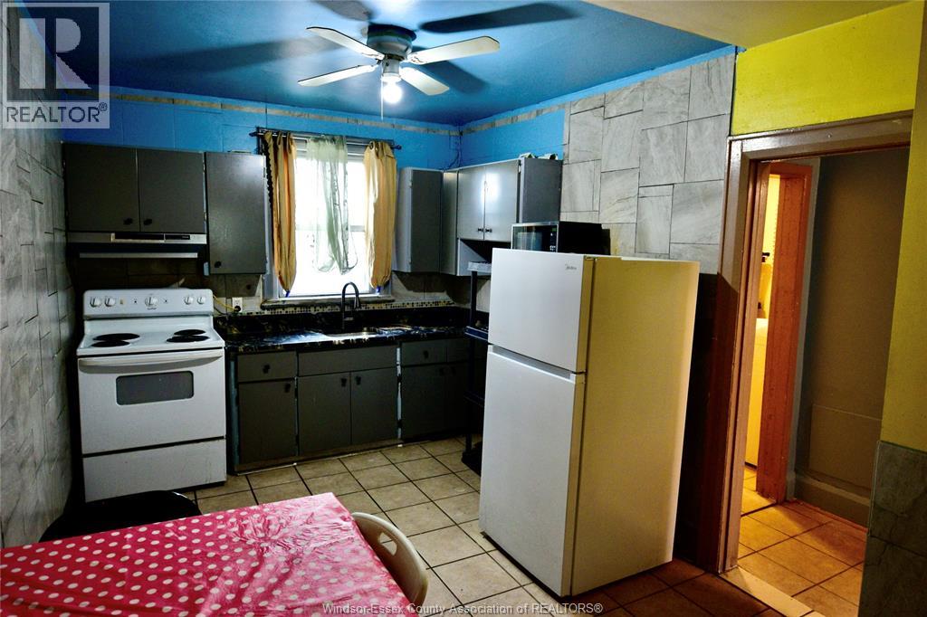 A kitchen with a white refrigerator and a red bedspread.