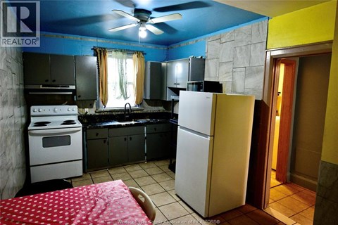 A kitchen with a white refrigerator and a red bedspread.