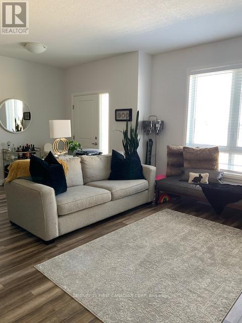A living room with a white couch and a grey rug.