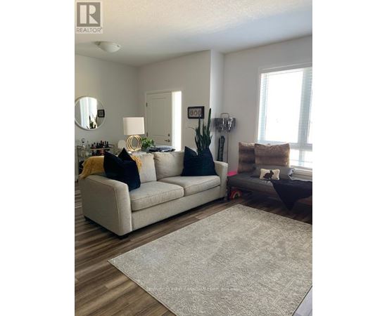 A living room with a white couch and a grey rug.