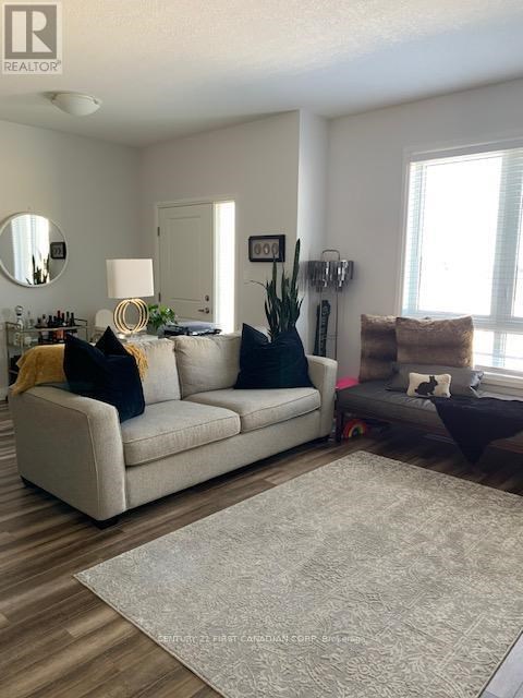 A living room with a white couch and a grey rug.