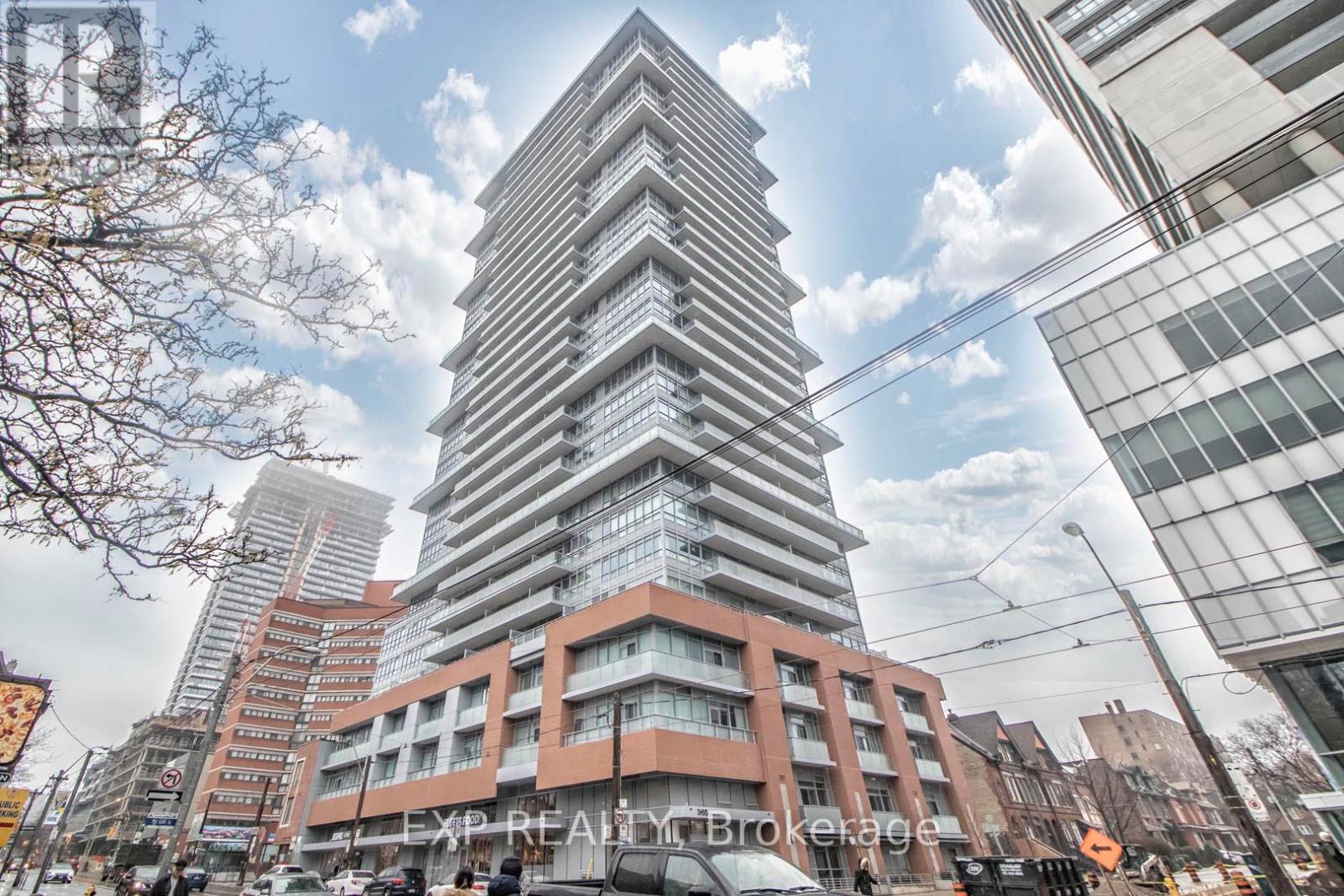 A tall, modern building with a curved design stands in the center of a bustling city street.