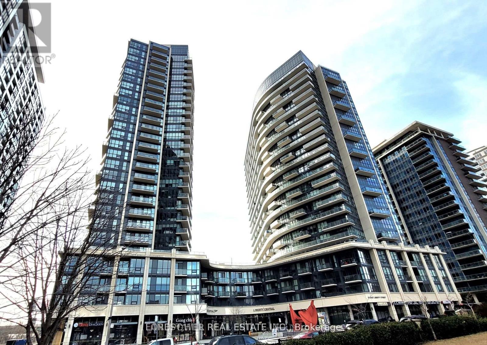 Two modern high-rise buildings are in the foreground with a clear sky above.