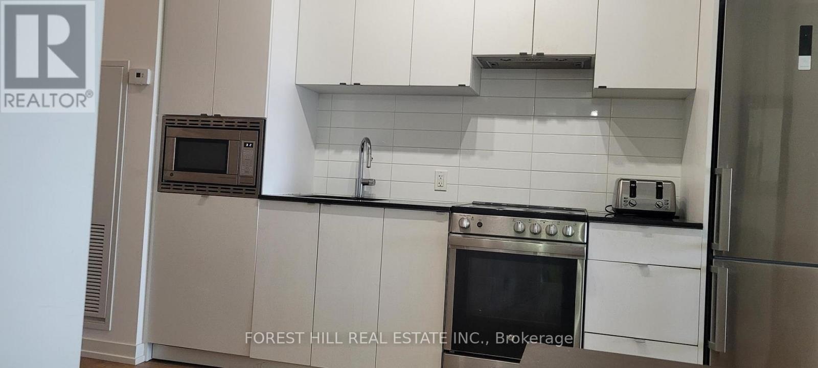 A kitchen with white cabinets and a stainless steel refrigerator.