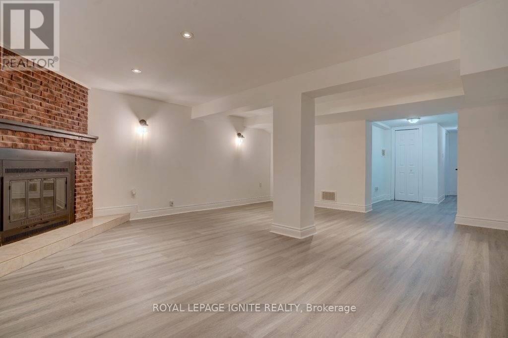 A spacious room with a fireplace and wooden flooring.